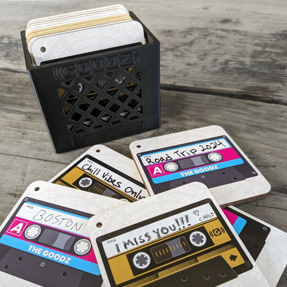 Six cassette-themed Mixtape Goodz cards fanned out beside a black GOODZ mini milk crate on a wood surface.